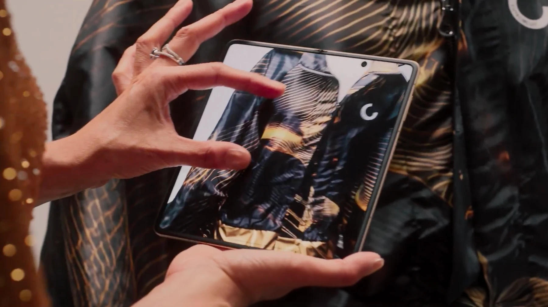 Francesca using the HONOR Magic V5 to examine the black and gold garment print