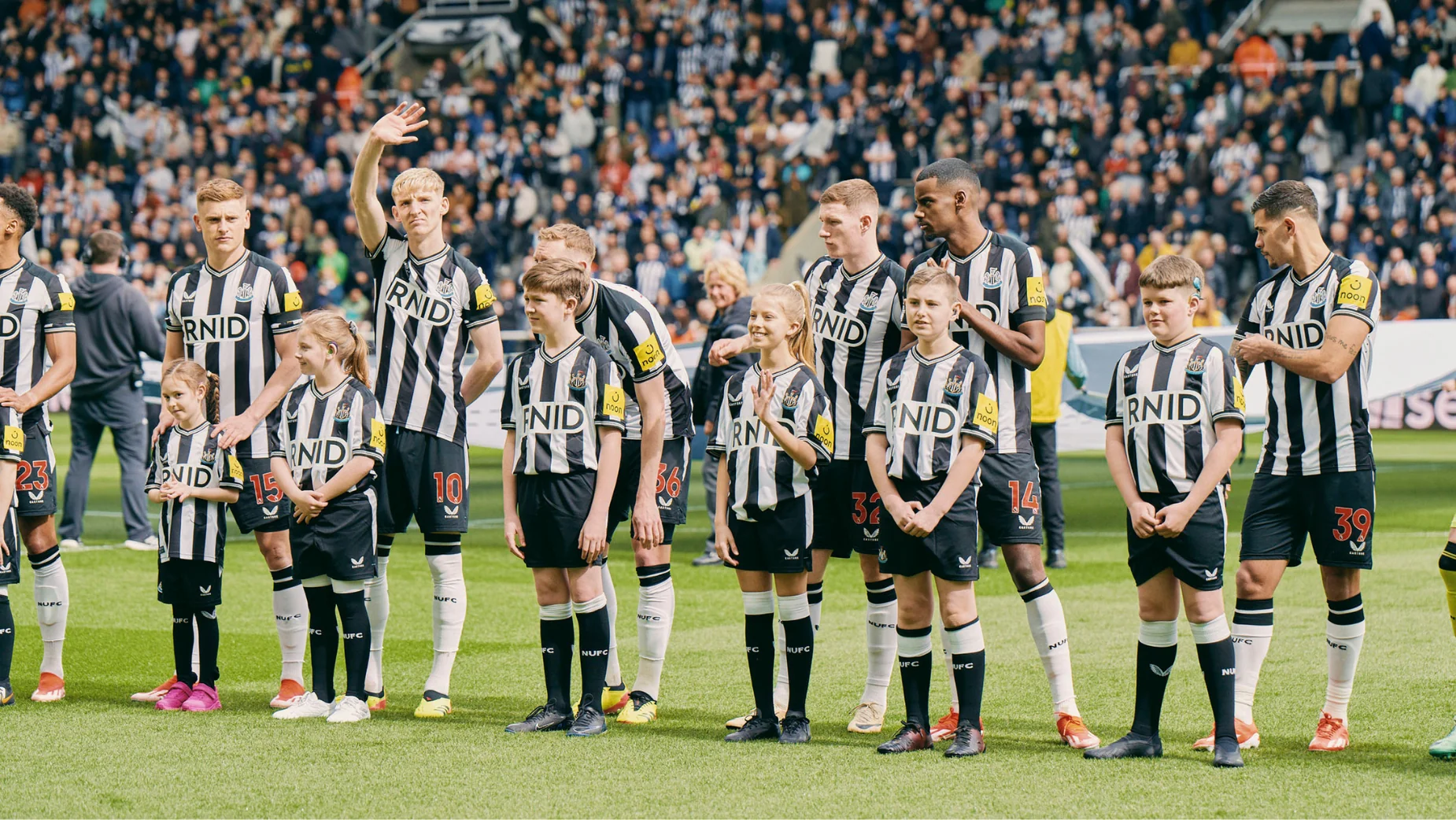 Newcastle United players with children wearing SoundShirts on the pitch